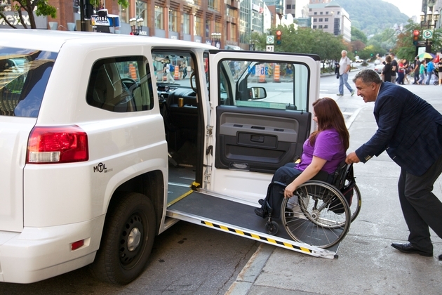 Une femme en fauteuil entre dans un taxi adapté