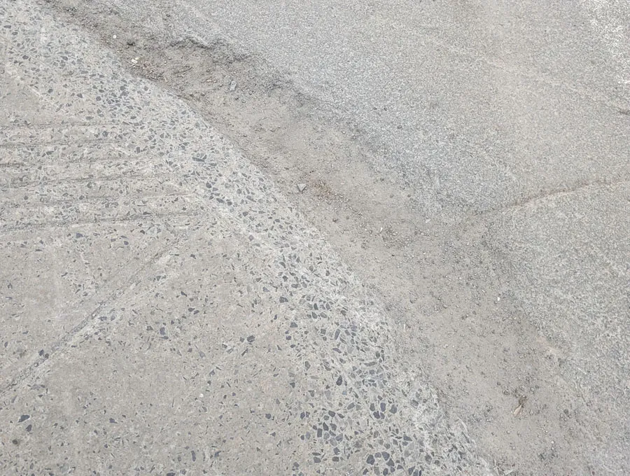 Bordure de trottoir dégradée avec pente irrégulière et surface endommagée rendant la transition difficile vers la chaussée.