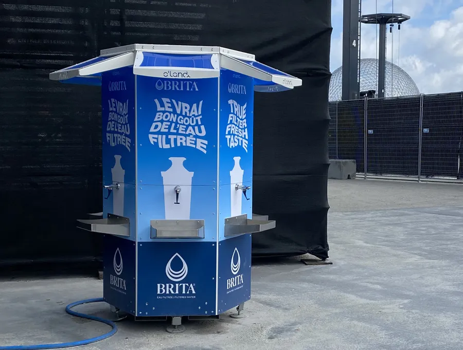 Station de remplissage d’eau avec plusieurs robinets et tablettes, installée sur une surface plane.