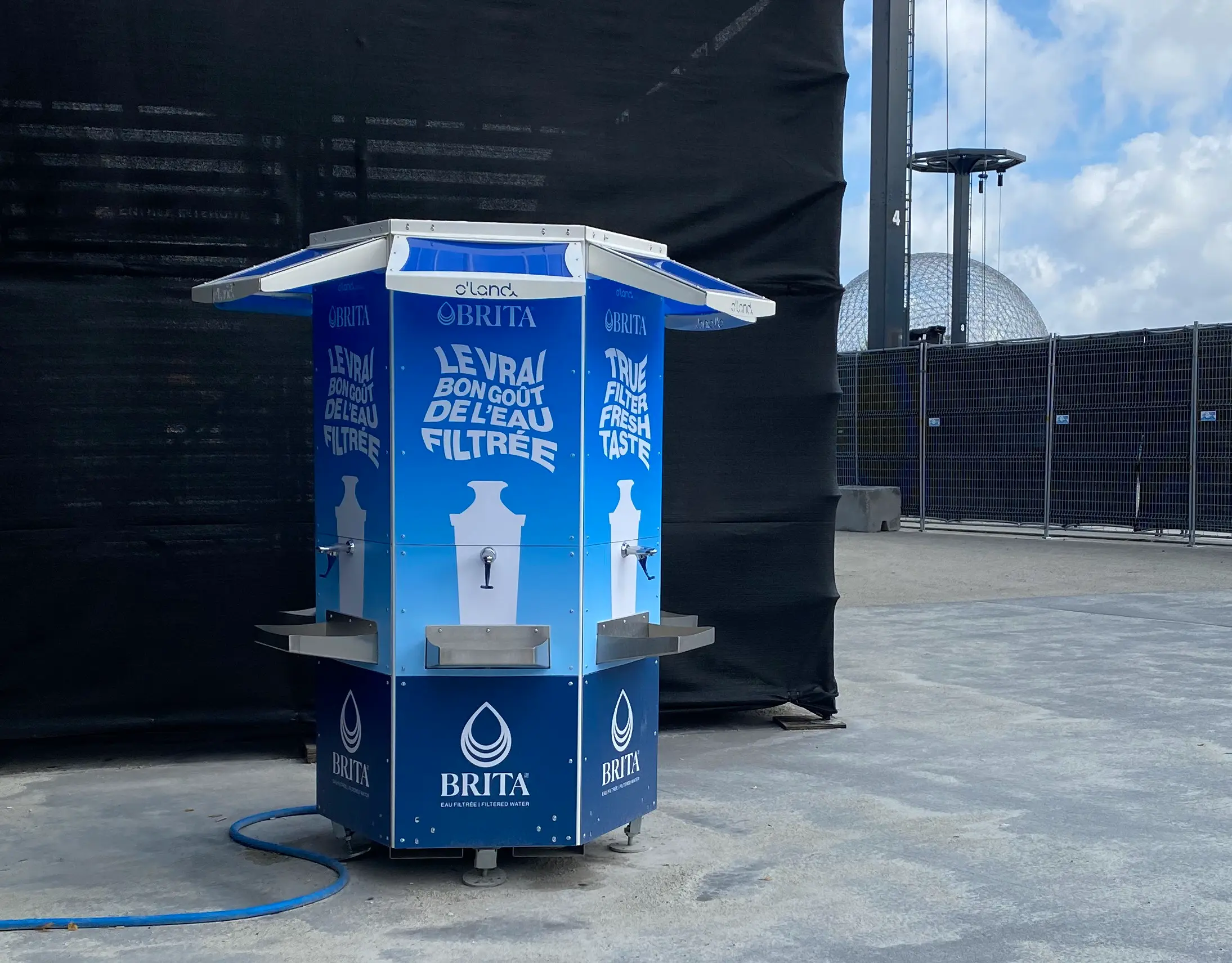 Station de remplissage d’eau avec plusieurs robinets et tablettes, installée sur une surface plane.