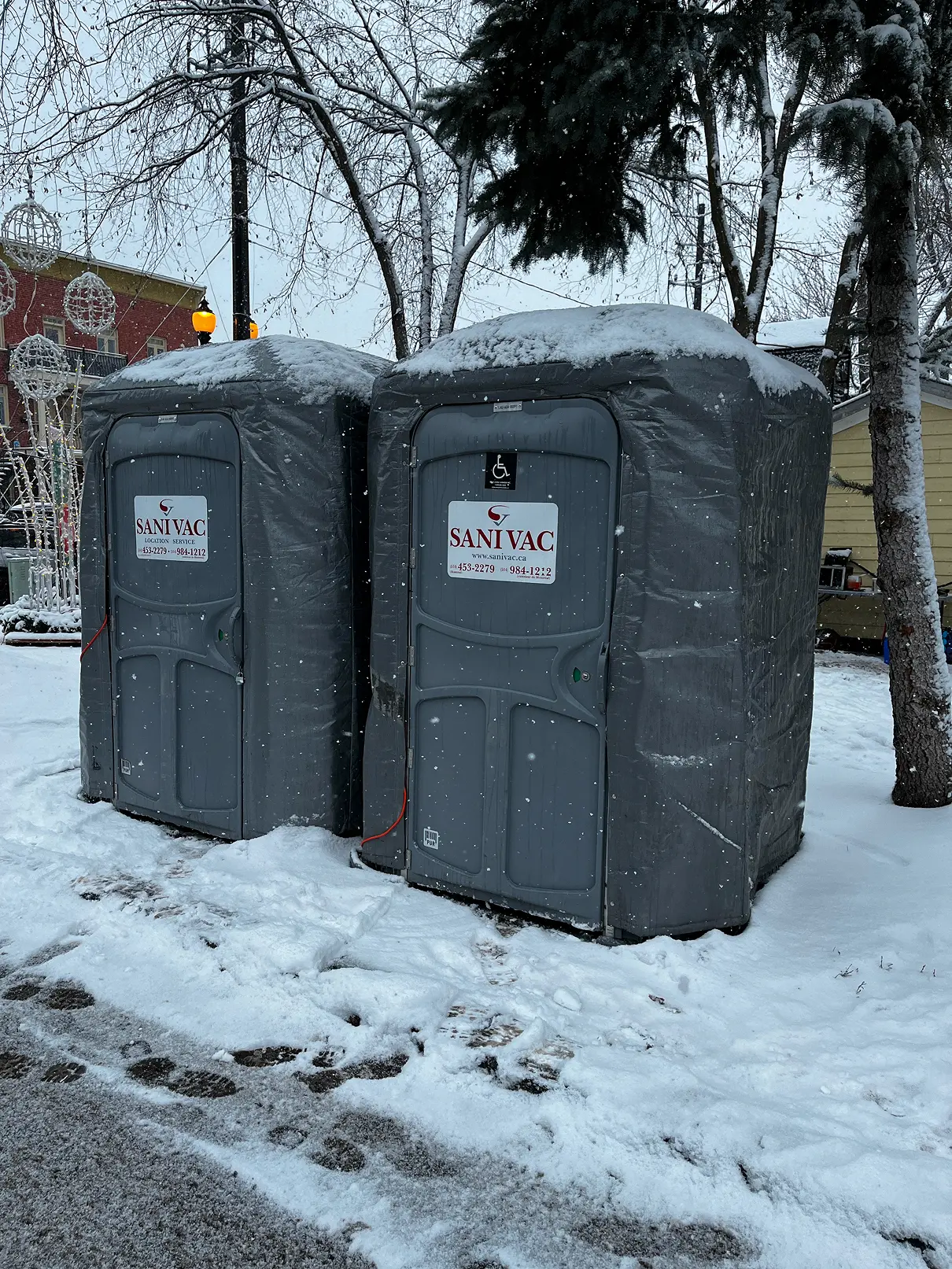 Deux toilettes chimiques extérieures dans la neige, dont une identifiée par le symbole international d’accessibilité.