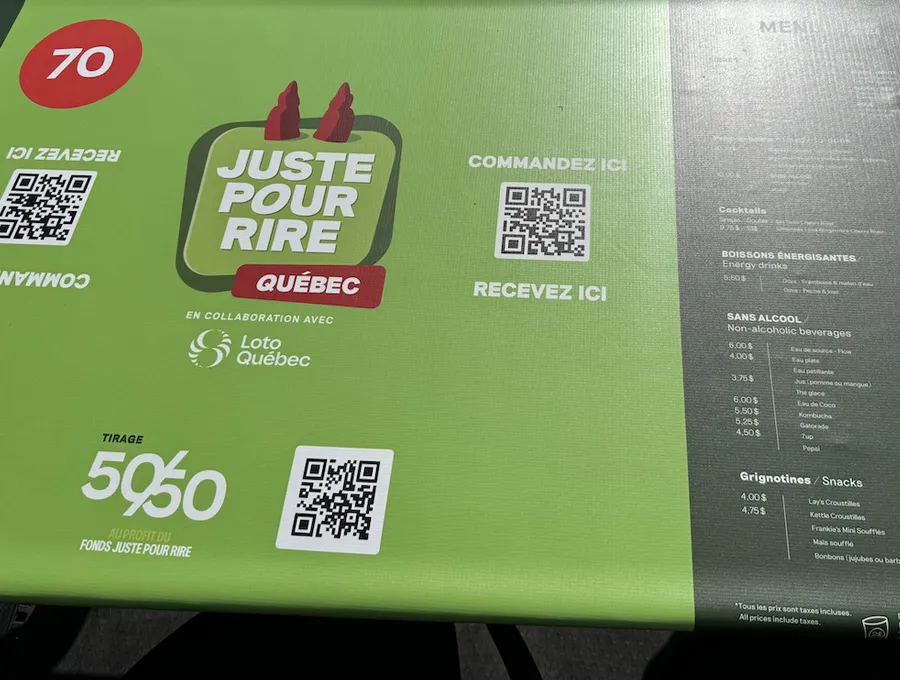 Comptoir vert avec un menu et des codes QR permettant de commander et de recevoir des boissons.