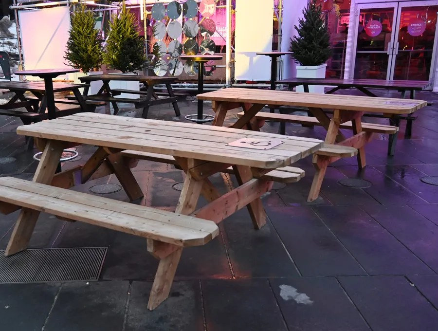 Table de pique-nique en bois avec une extrémité sans banc, identifiée par le symbole international d’accessibilité.