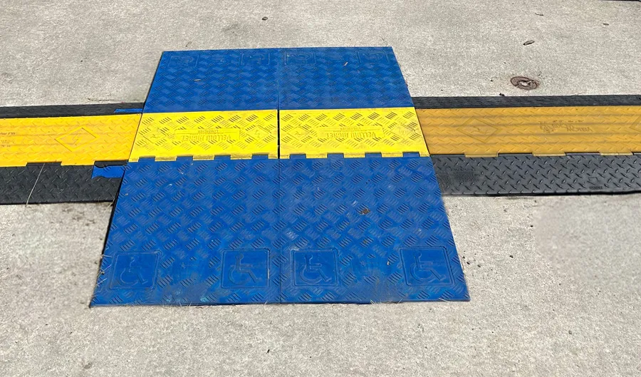 Chemin extérieur en béton avec passe-fils surélevé, une section munie de côtés plus longs réduit l’inclinaison de la pente et se distingue par une couleur bleue contrastée.