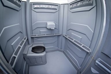 Intérieur gris d'une toilette chimique accessible. Grand espace, barre d'appui.